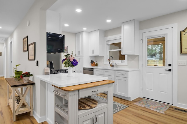 kitchen with light wood-type flooring, visible vents, a sink, recessed lighting, and white cabinets