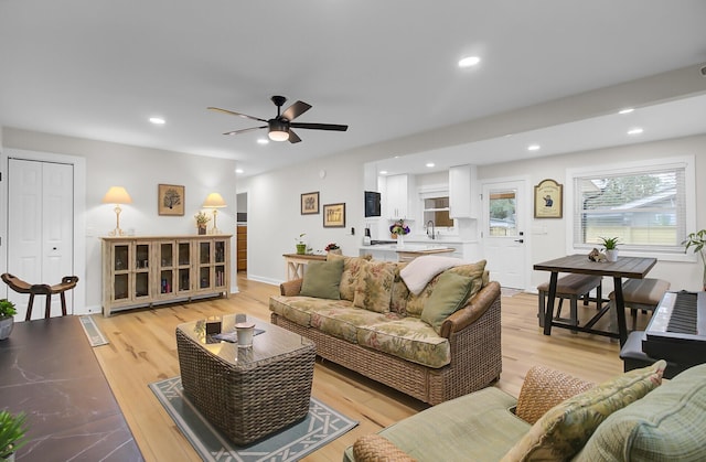 living area featuring a ceiling fan, recessed lighting, light wood-style floors, and baseboards