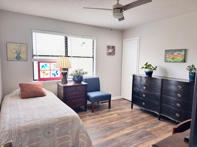 bedroom with baseboards, a textured ceiling, a ceiling fan, and wood finished floors