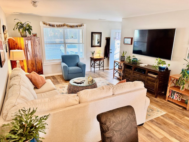 living area featuring baseboards and light wood-type flooring