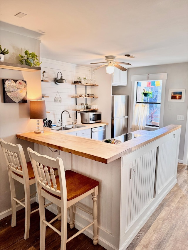 kitchen featuring a sink, light wood-style flooring, appliances with stainless steel finishes, and open shelves