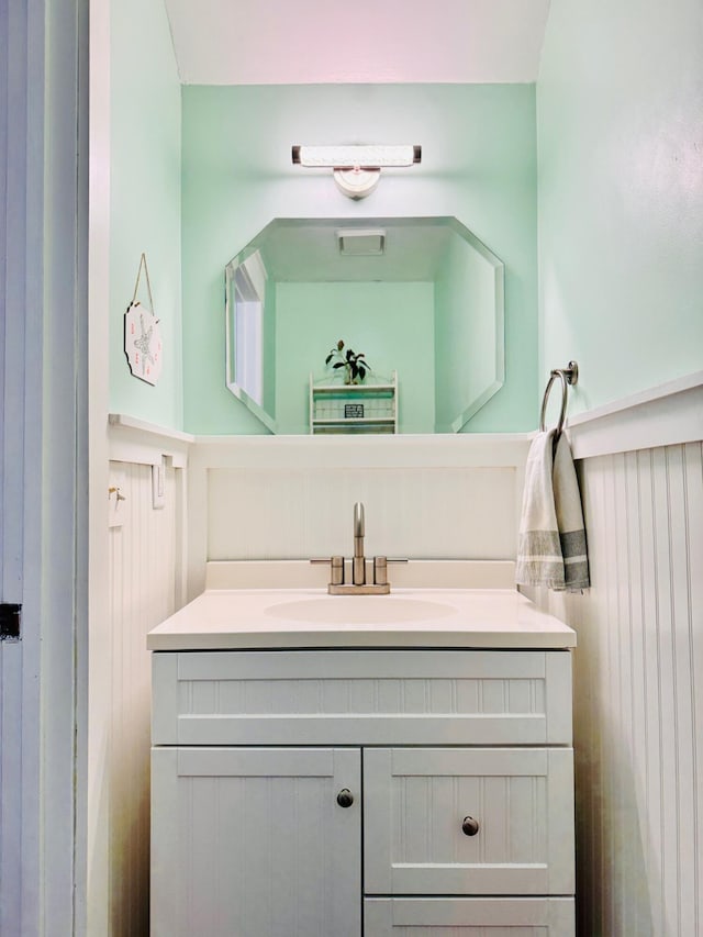 bathroom with vanity and a wainscoted wall