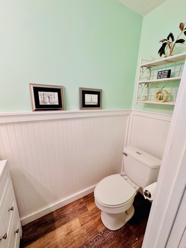 bathroom featuring toilet, wood finished floors, and wainscoting