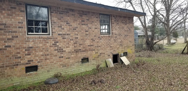 view of side of property featuring crawl space and brick siding