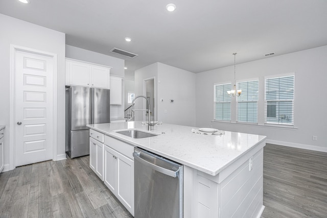 kitchen featuring stainless steel appliances, a center island with sink, and white cabinets