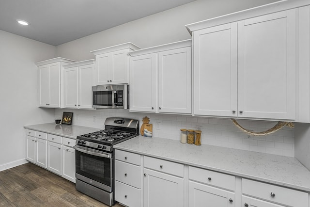 kitchen featuring stainless steel appliances, white cabinetry, dark hardwood / wood-style floors, decorative backsplash, and light stone countertops