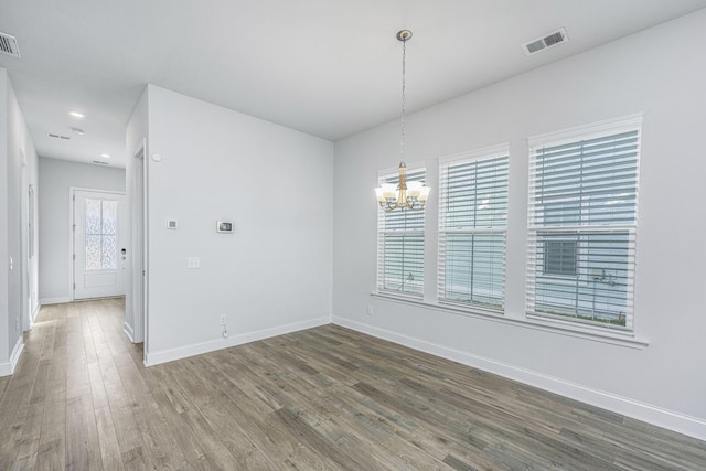 spare room with dark hardwood / wood-style flooring and a chandelier