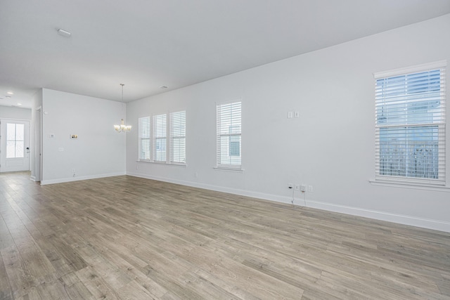 unfurnished room with a chandelier and light hardwood / wood-style flooring