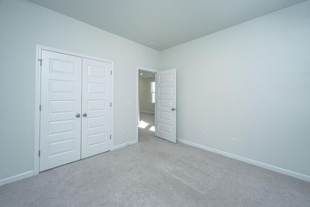 unfurnished bedroom with a closet and light carpet