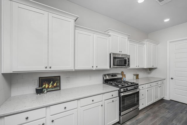 kitchen featuring light stone countertops, stainless steel appliances, tasteful backsplash, dark hardwood / wood-style flooring, and white cabinetry