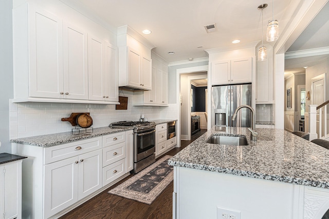 kitchen with dark wood-type flooring, white cabinets, sink, appliances with stainless steel finishes, and decorative light fixtures