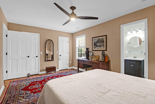 bedroom with connected bathroom, ceiling fan, and hardwood / wood-style floors