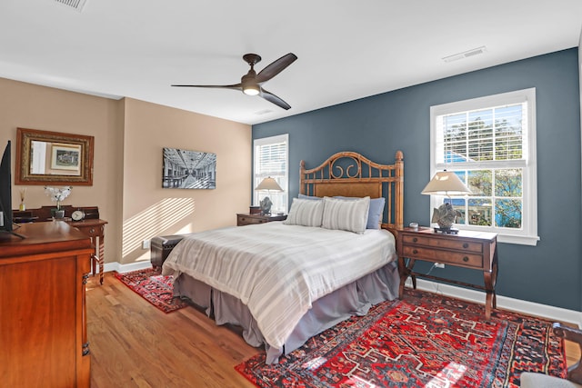 bedroom featuring hardwood / wood-style flooring, multiple windows, and ceiling fan