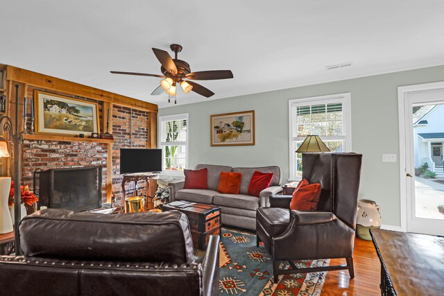 living room featuring a fireplace, wood-type flooring, ceiling fan, and a healthy amount of sunlight