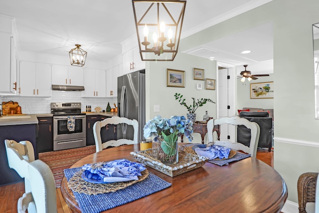 dining area featuring ceiling fan with notable chandelier, dark hardwood / wood-style floors, sink, and crown molding