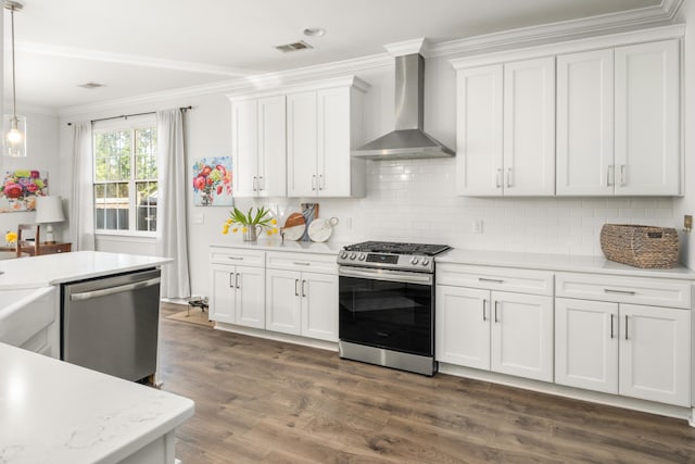 kitchen with wall chimney range hood, white cabinetry, appliances with stainless steel finishes, crown molding, and light countertops