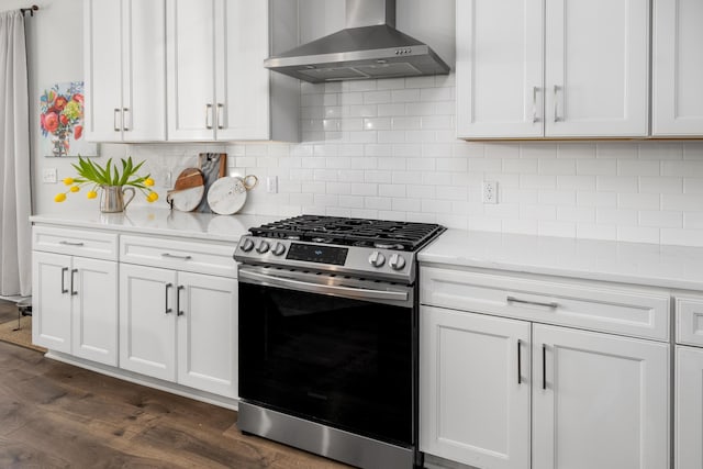 kitchen featuring stainless steel range with gas cooktop, dark wood finished floors, white cabinetry, wall chimney exhaust hood, and tasteful backsplash