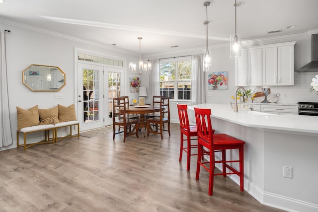 kitchen featuring ornamental molding, wood finished floors, wall chimney range hood, decorative backsplash, and stove