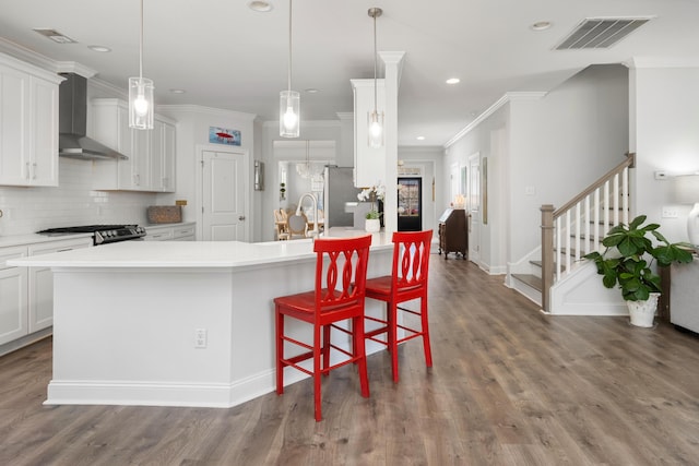 kitchen with dark wood-type flooring, wall chimney range hood, visible vents, and backsplash