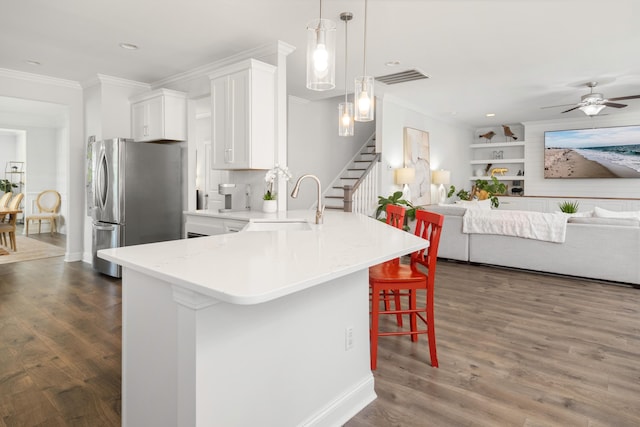 kitchen featuring a breakfast bar, ornamental molding, freestanding refrigerator, white cabinets, and dark wood-style flooring