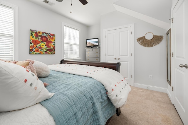 bedroom with visible vents, lofted ceiling, a closet, baseboards, and light colored carpet