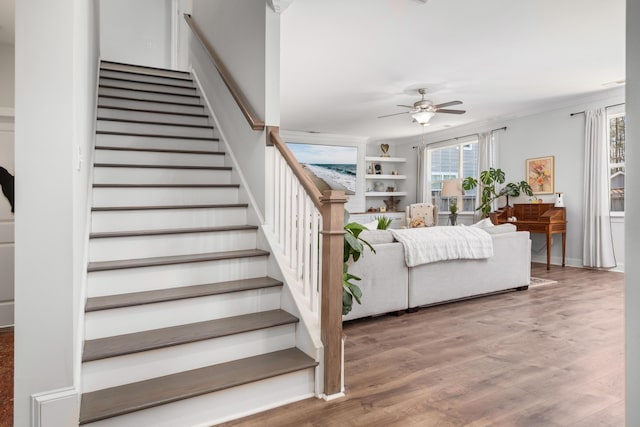 staircase featuring ornamental molding, wood finished floors, and ceiling fan