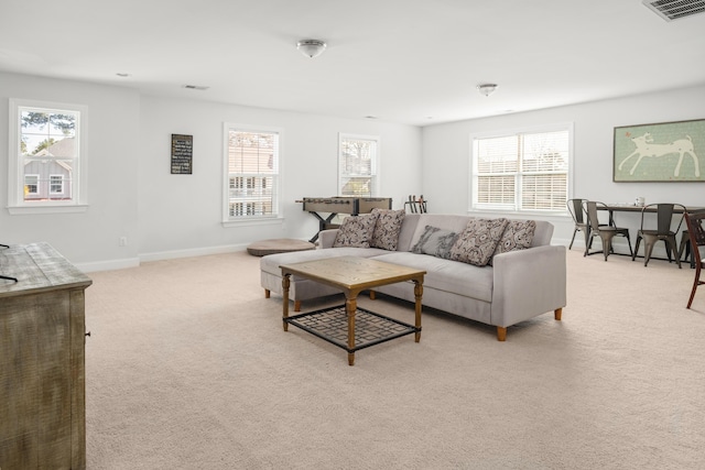 living room with light colored carpet, visible vents, a wealth of natural light, and baseboards