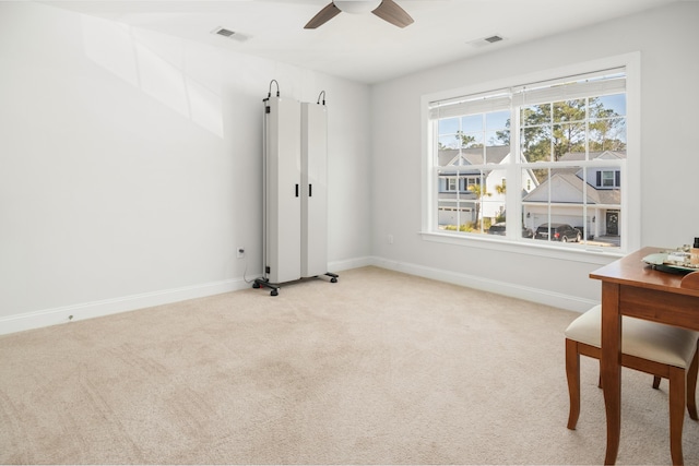 interior space featuring baseboards, a ceiling fan, visible vents, and light carpet