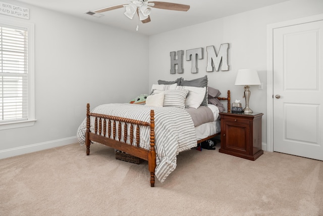 bedroom with ceiling fan, light colored carpet, visible vents, and baseboards