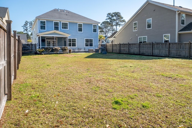 back of property with a fenced backyard and a yard