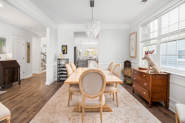 dining area featuring a notable chandelier, ornamental molding, stairway, wainscoting, and dark wood-style flooring