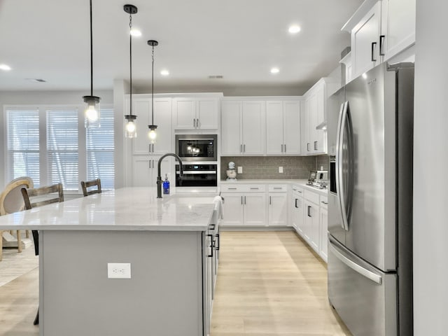 kitchen featuring white cabinetry, appliances with stainless steel finishes, a breakfast bar, and a kitchen island with sink