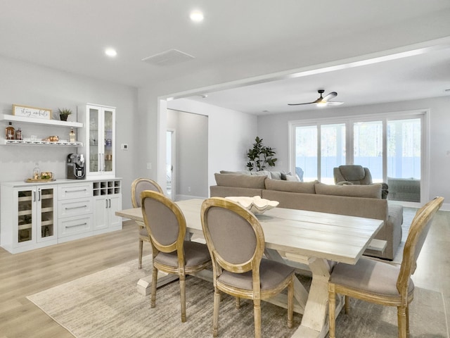 dining area with ceiling fan, bar area, and light hardwood / wood-style floors