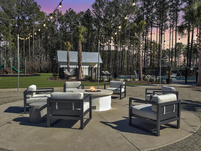 patio terrace at dusk featuring an outdoor fire pit and a playground