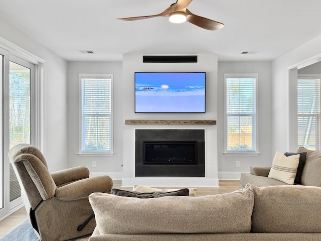 living room with ceiling fan, light wood-type flooring, and a wealth of natural light