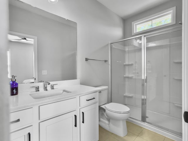 bathroom with vanity, a shower with door, tile patterned floors, and toilet