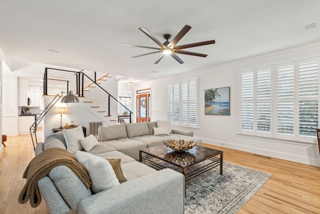 living room with light hardwood / wood-style floors, ceiling fan, and ornamental molding