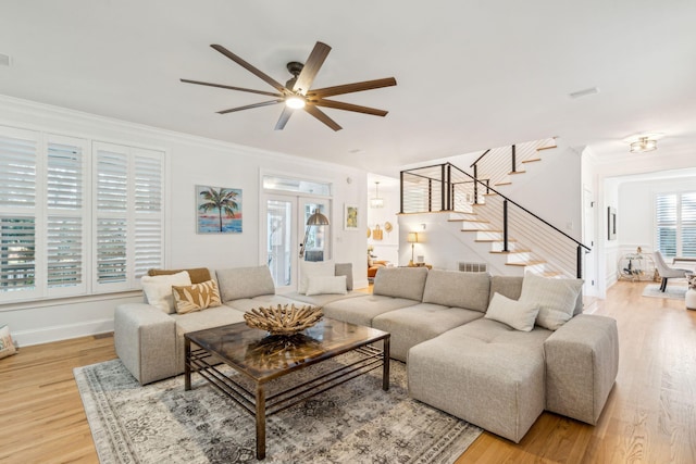 living room with ceiling fan, wood-type flooring, ornamental molding, and french doors