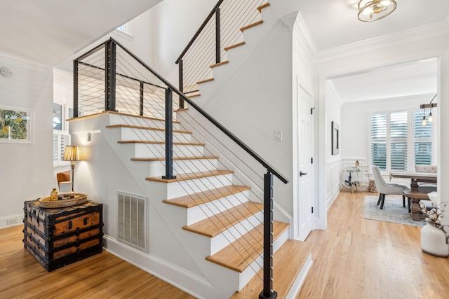 staircase with wood-type flooring and crown molding