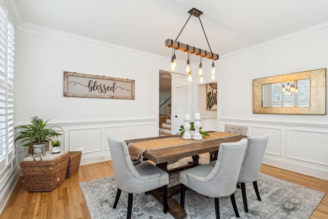 dining space with a notable chandelier, ornamental molding, and light hardwood / wood-style flooring