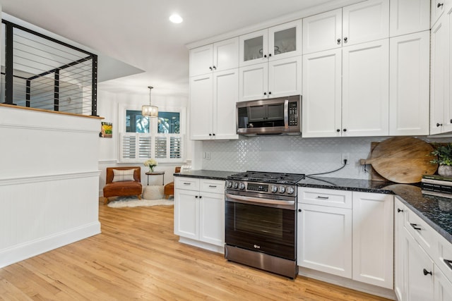 kitchen featuring light wood-type flooring, stainless steel appliances, white cabinetry, and hanging light fixtures