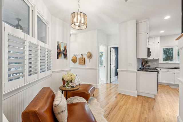 kitchen featuring white cabinetry, light hardwood / wood-style flooring, a chandelier, and decorative light fixtures