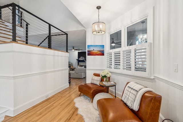 sitting room with hardwood / wood-style floors and ceiling fan with notable chandelier