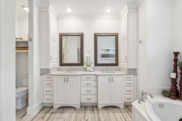 bathroom featuring hardwood / wood-style floors, vanity, a bathing tub, crown molding, and toilet