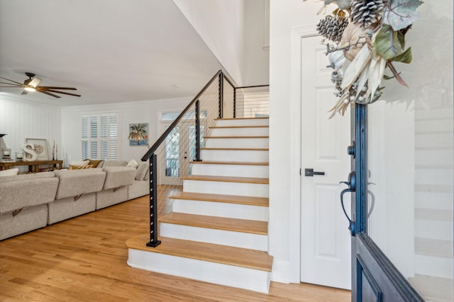 stairway featuring wood-type flooring, ceiling fan, and ornamental molding