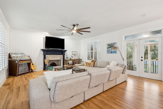 living room with a fireplace, light wood-type flooring, ceiling fan, and ornamental molding