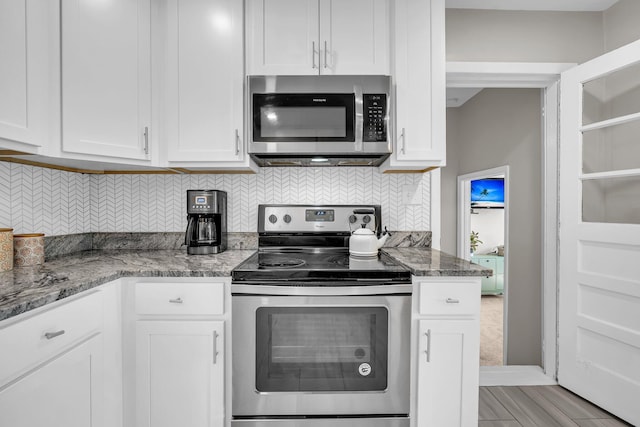 kitchen featuring tasteful backsplash, white cabinetry, stainless steel appliances, and light stone countertops