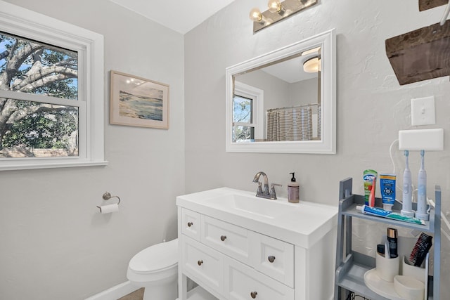 bathroom with toilet, vanity, and baseboards