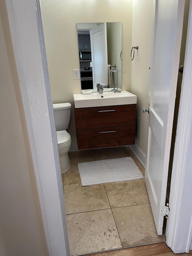 bathroom with toilet, baseboards, and vanity