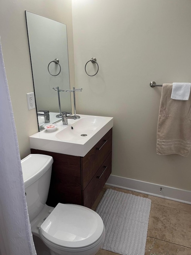 half bath featuring baseboards, vanity, and toilet